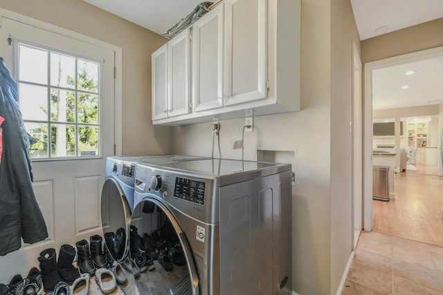 laundry room with washing machine and dryer, cabinet space, and light tile patterned floors
