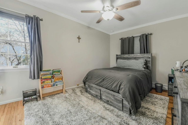 bedroom featuring baseboards, ornamental molding, wood finished floors, and multiple windows