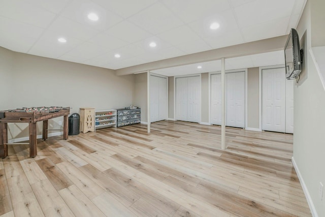 finished basement with a paneled ceiling, recessed lighting, baseboards, and light wood-type flooring