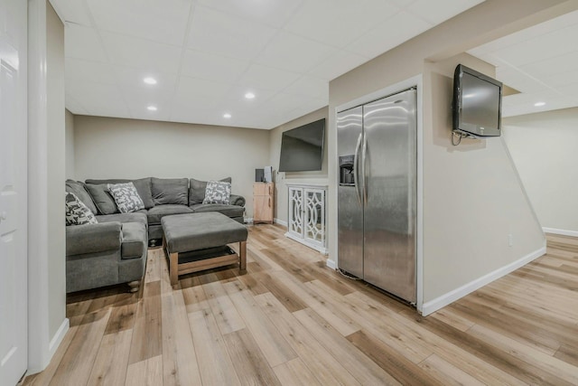 living area featuring baseboards, light wood-style floors, recessed lighting, and a paneled ceiling