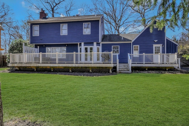 rear view of house featuring a chimney, a wooden deck, and a yard
