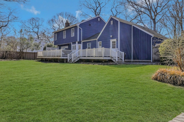 rear view of house featuring a wooden deck, fence, a yard, and a chimney