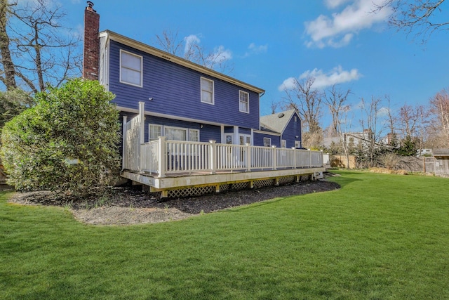 back of house featuring a chimney, fence, a wooden deck, and a yard