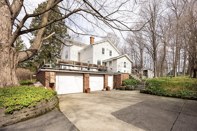 655 Vassar Rd, Poughkeepsie, NY 12603 - view of side of property with a garage, a chimney, stairs, brick siding, and driveway