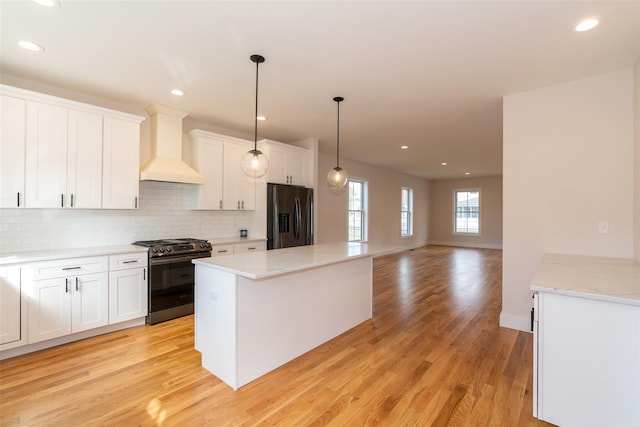 651 Vassar Rd, Poughkeepsie, NY 12603 - kitchen featuring a center island, backsplash, wall chimney exhaust hood, appliances with stainless steel finishes, and light wood finished floors