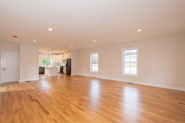651 Vassar Rd, Poughkeepsie, NY 12603 - unfurnished living room featuring light wood-style flooring, a healthy amount of sunlight, baseboards, and recessed lighting