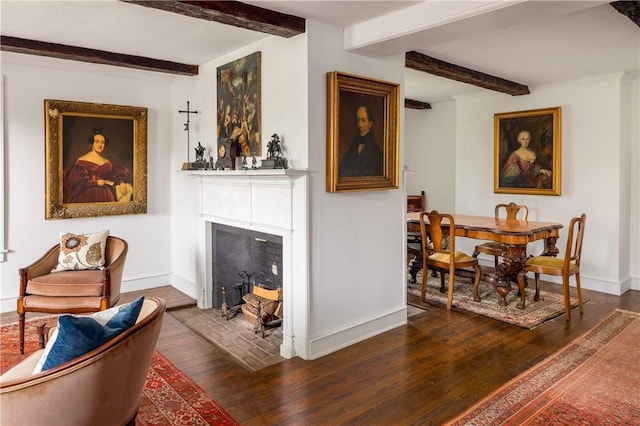living room featuring dark wood-type flooring, a fireplace with flush hearth, baseboards, and beam ceiling