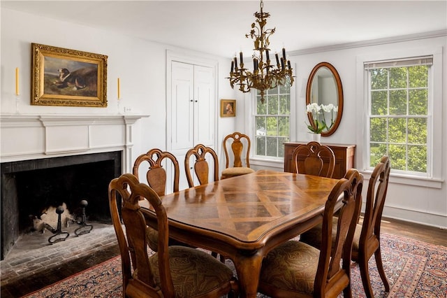 dining space featuring baseboards, a fireplace, a chandelier, and a wealth of natural light