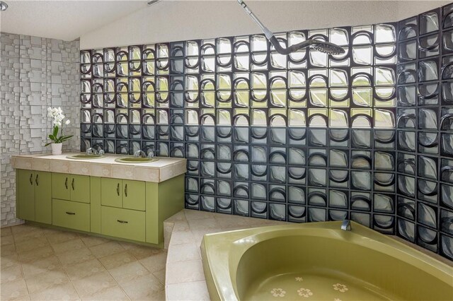 bathroom with tile patterned floors, lofted ceiling, a sink, and a bathtub