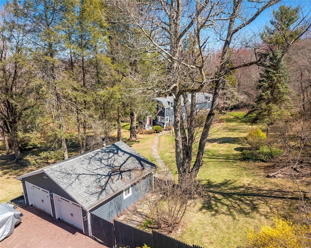 view of yard featuring a detached garage, fence, and dirt driveway