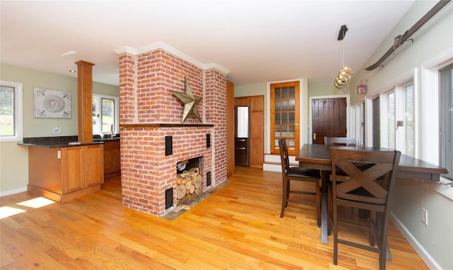 dining area with a brick fireplace, baseboards, and light wood finished floors