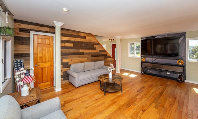 living area with baseboards, decorative columns, wooden walls, and a wealth of natural light