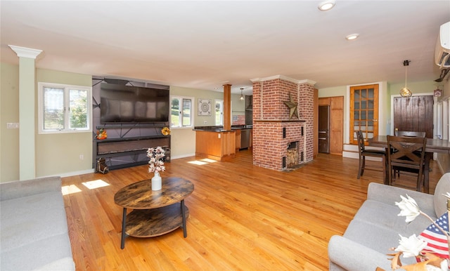 living area featuring baseboards, a fireplace, light wood finished floors, and a wealth of natural light