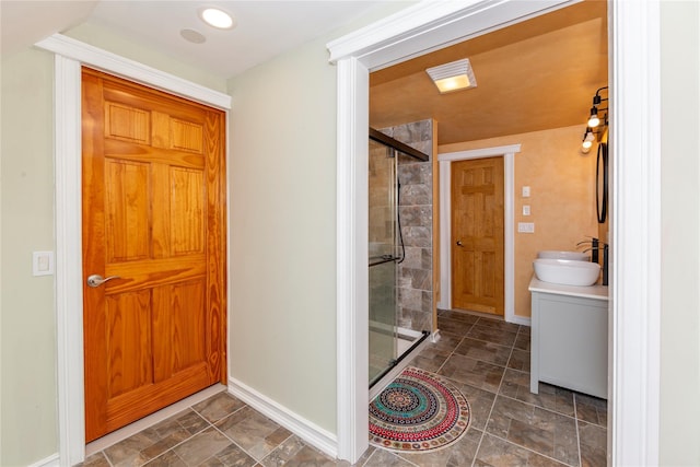 full bath featuring vanity, baseboards, a shower stall, and stone finish flooring