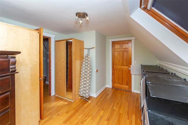 additional living space with light wood-style flooring and vaulted ceiling