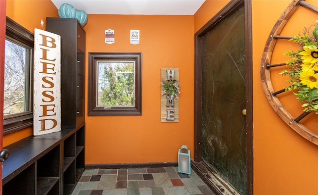 entryway featuring baseboards, stone finish flooring, and a healthy amount of sunlight