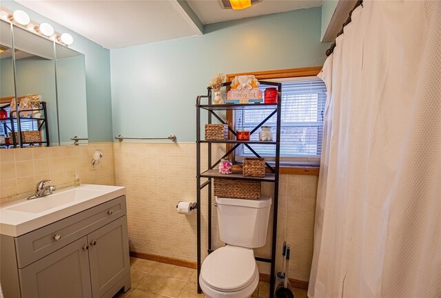 bathroom featuring tile patterned floors, toilet, tile walls, and wainscoting