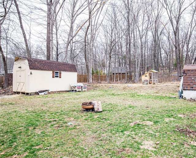 view of yard with an outdoor structure, an outdoor fire pit, a storage shed, and fence