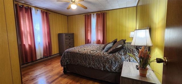 22 Ballard St, Smallwood, NY 12778 - bedroom with baseboard heating, multiple windows, wooden walls, a ceiling fan, and wood finished floors