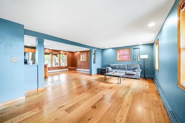 living area with baseboards, light wood finished floors, baseboard heating, and a baseboard radiator