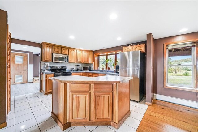 kitchen featuring light tile patterned flooring, a kitchen island, appliances with stainless steel finishes, baseboards, and recessed lighting