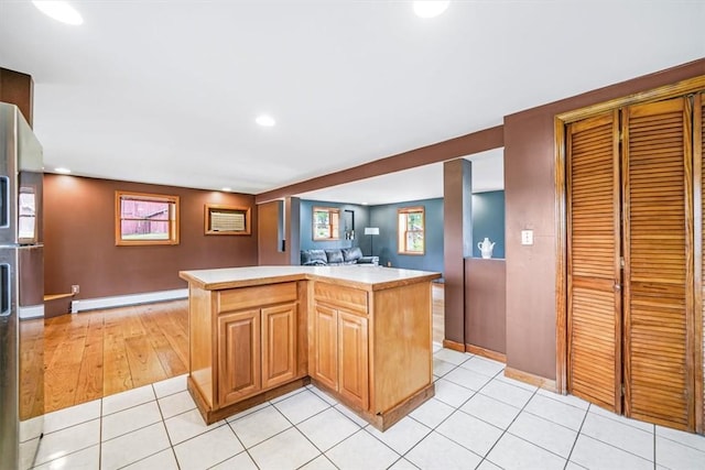 kitchen with light countertops, baseboard heating, open floor plan, a center island, and light tile patterned floors