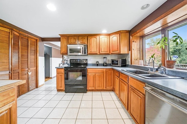 kitchen featuring a sink, appliances with stainless steel finishes, brown cabinetry, light tile patterned floors, and decorative backsplash