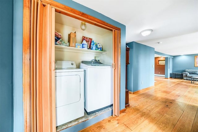 laundry area featuring light wood finished floors, baseboards, a baseboard radiator, and washing machine and clothes dryer