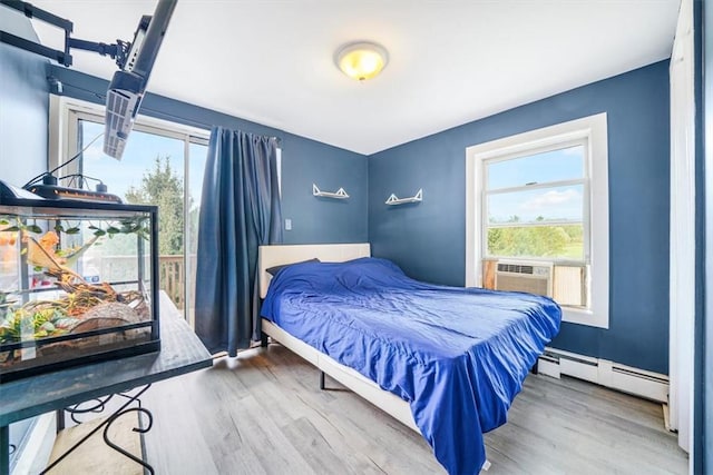 bedroom with baseboards, baseboard heating, and wood finished floors