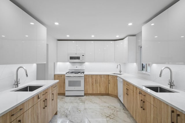 kitchen featuring modern cabinets, white appliances, a sink, and marble finish floor