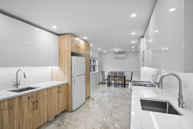 kitchen featuring a wall mounted air conditioner, a sink, modern cabinets, marble finish floor, and freestanding refrigerator