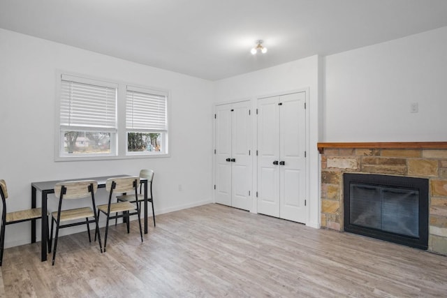 home office with wood finished floors, baseboards, and a stone fireplace