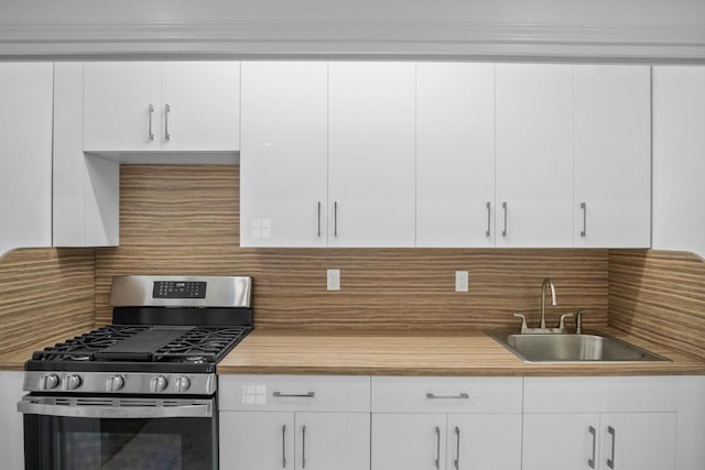 kitchen with a sink, light countertops, backsplash, white cabinetry, and gas stove