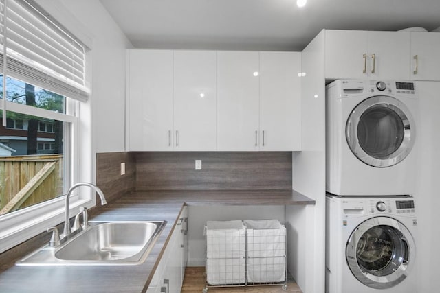 clothes washing area with stacked washer and clothes dryer and a sink