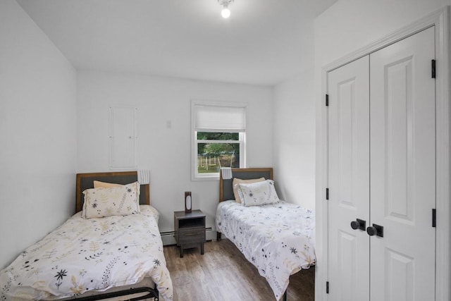 bedroom featuring light wood finished floors, a closet, and a baseboard heating unit