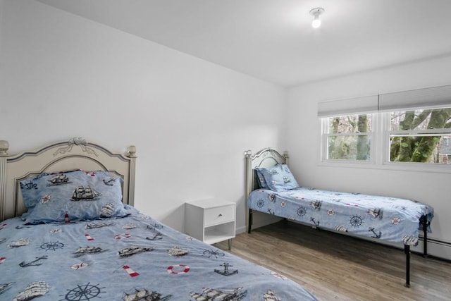 bedroom featuring wood finished floors, baseboards, and baseboard heating