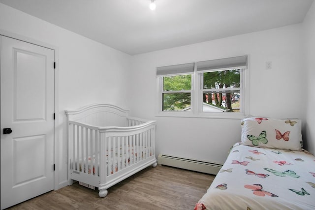 bedroom featuring baseboard heating and wood finished floors