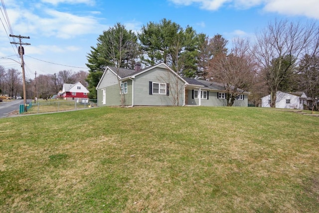 rear view of house with a yard, a chimney, and fence