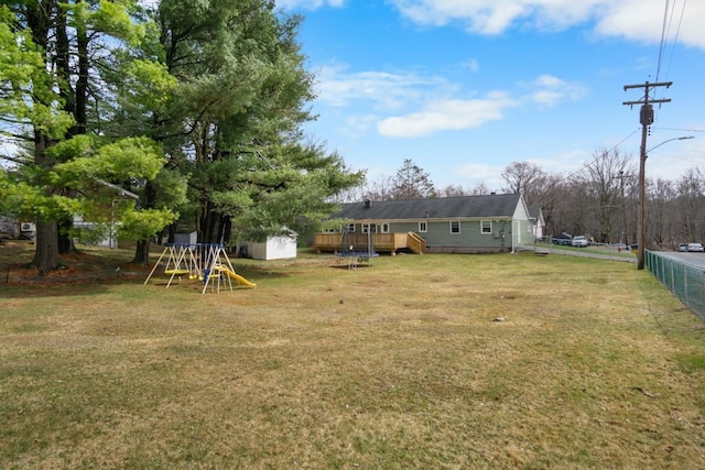 view of yard featuring a playground, fence, and a deck