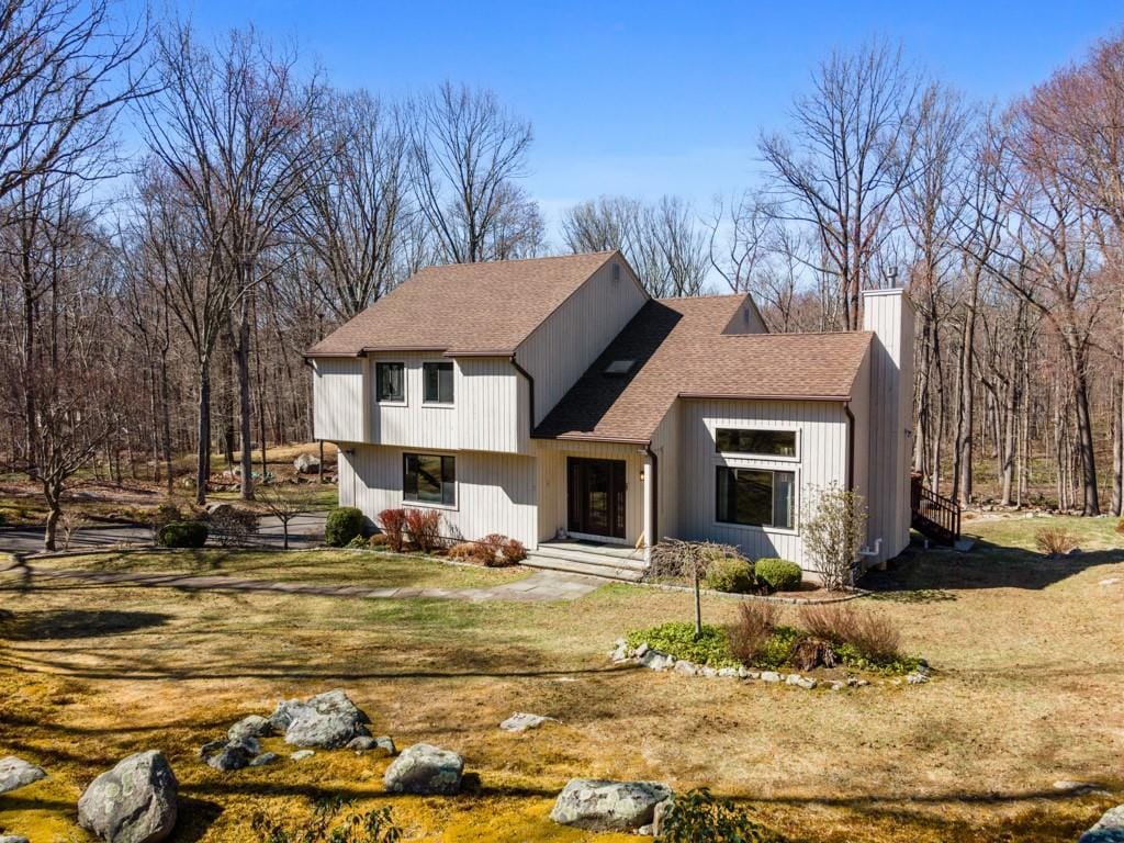 tri-level home with a front yard, a chimney, and a shingled roof