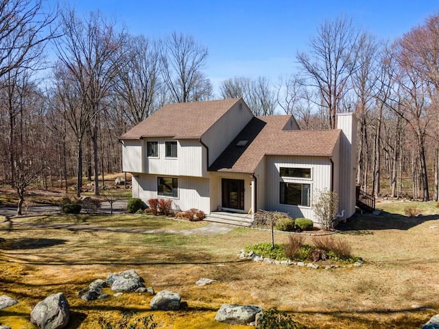 tri-level home with a front yard, a chimney, and a shingled roof