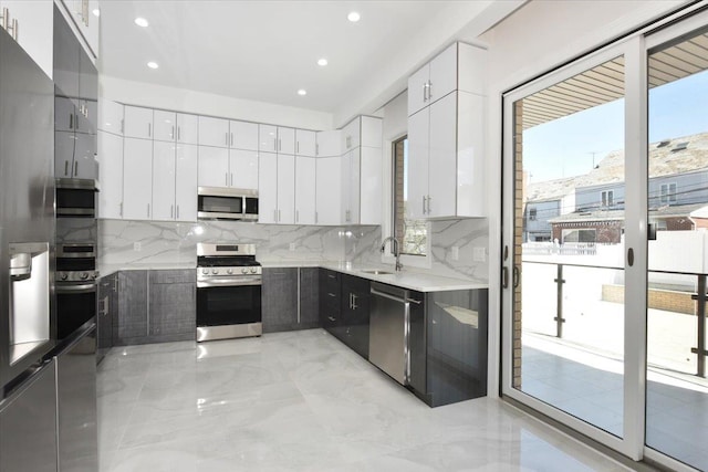 76-47 173rd St, Fresh Meadows, NY 11366 - kitchen featuring a sink, backsplash, appliances with stainless steel finishes, and white cabinetry