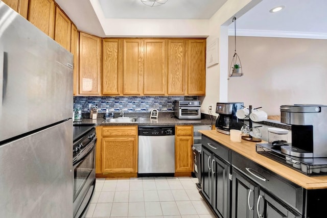 kitchen featuring crown molding, light tile patterned flooring, a sink, stainless steel appliances, and backsplash
