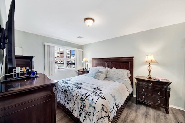 bedroom featuring visible vents, baseboards, and dark wood-style floors