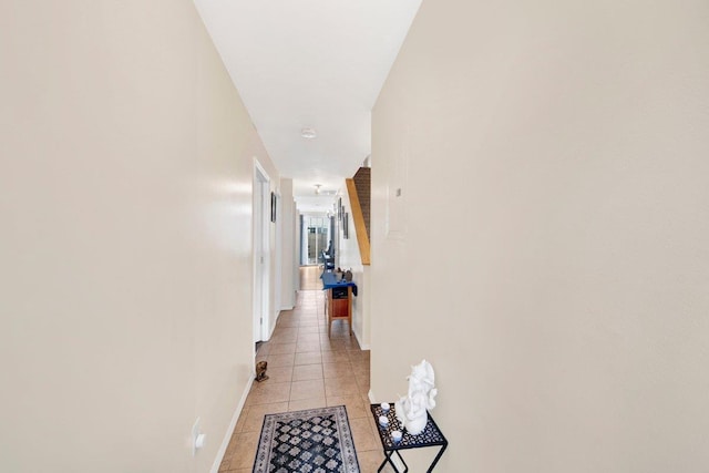 hallway featuring baseboards and light tile patterned floors