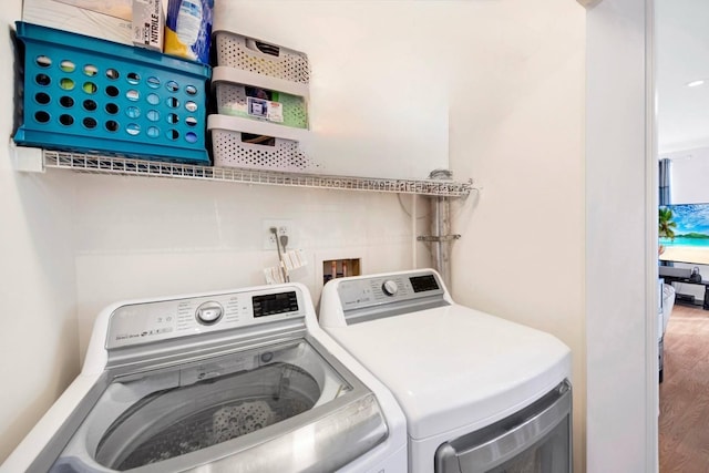 washroom with separate washer and dryer, laundry area, and wood finished floors