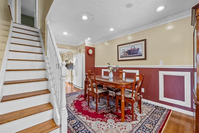 dining area featuring baseboards, ornamental molding, light wood-type flooring, recessed lighting, and stairs