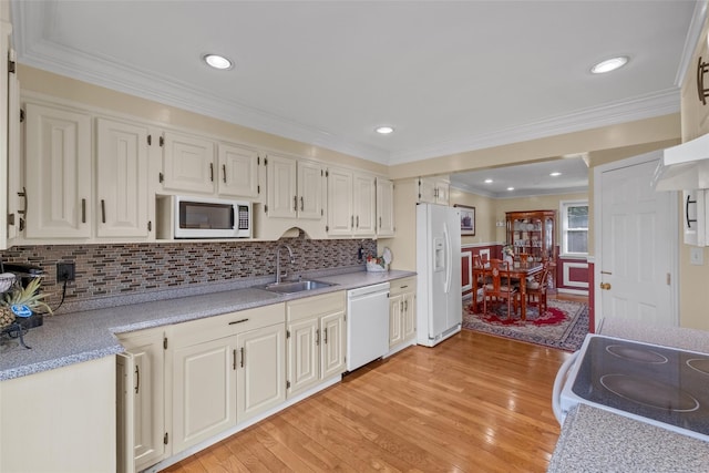 kitchen featuring white appliances, light countertops, a sink, and light wood finished floors