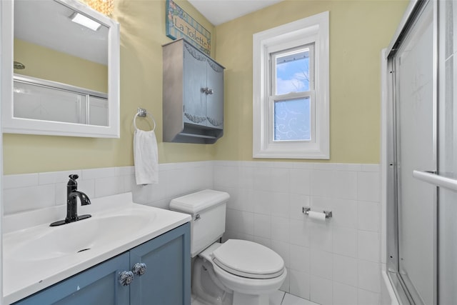 full bathroom featuring vanity, a wainscoted wall, toilet, tile walls, and an enclosed shower