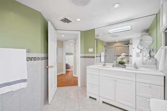 full bathroom with a shower stall, visible vents, tile walls, and a sink